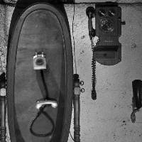 antique telephones and collapsed figure in black and white photo